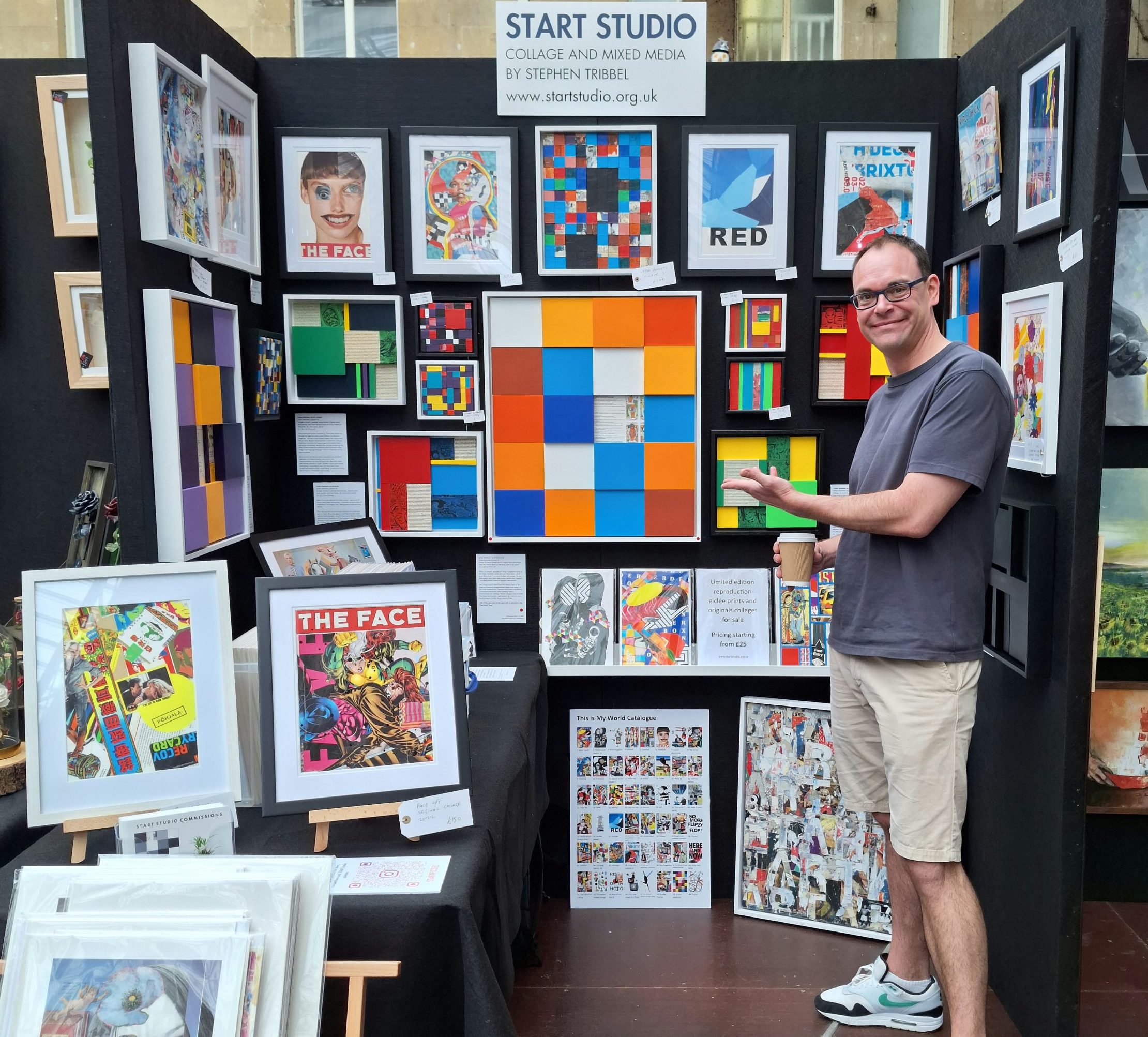 Artist Stephen Tribbel in front of Start Studio's stall with original framed artwork hung on black walls at Bath Contemporary Art Fair Sunday 8th September 2024.